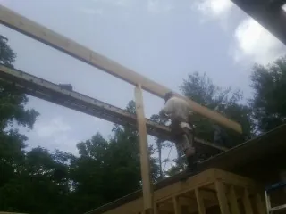 Carpenter setting a ridge beam over a new addition frame — Ice Dam Removal by Roofing Brothers in Boxholm