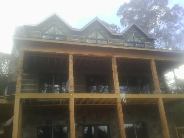 Dormers and porch framing on a large log home under construction — Roof Coating work by our crew in Boxholm