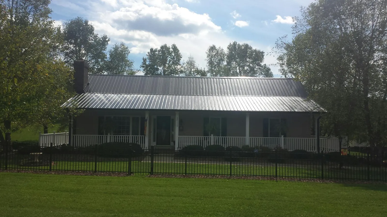 Gray metal roof on a brick ranch with a full width front porch — Gutter Guard Installation work by our crew in Boxholm