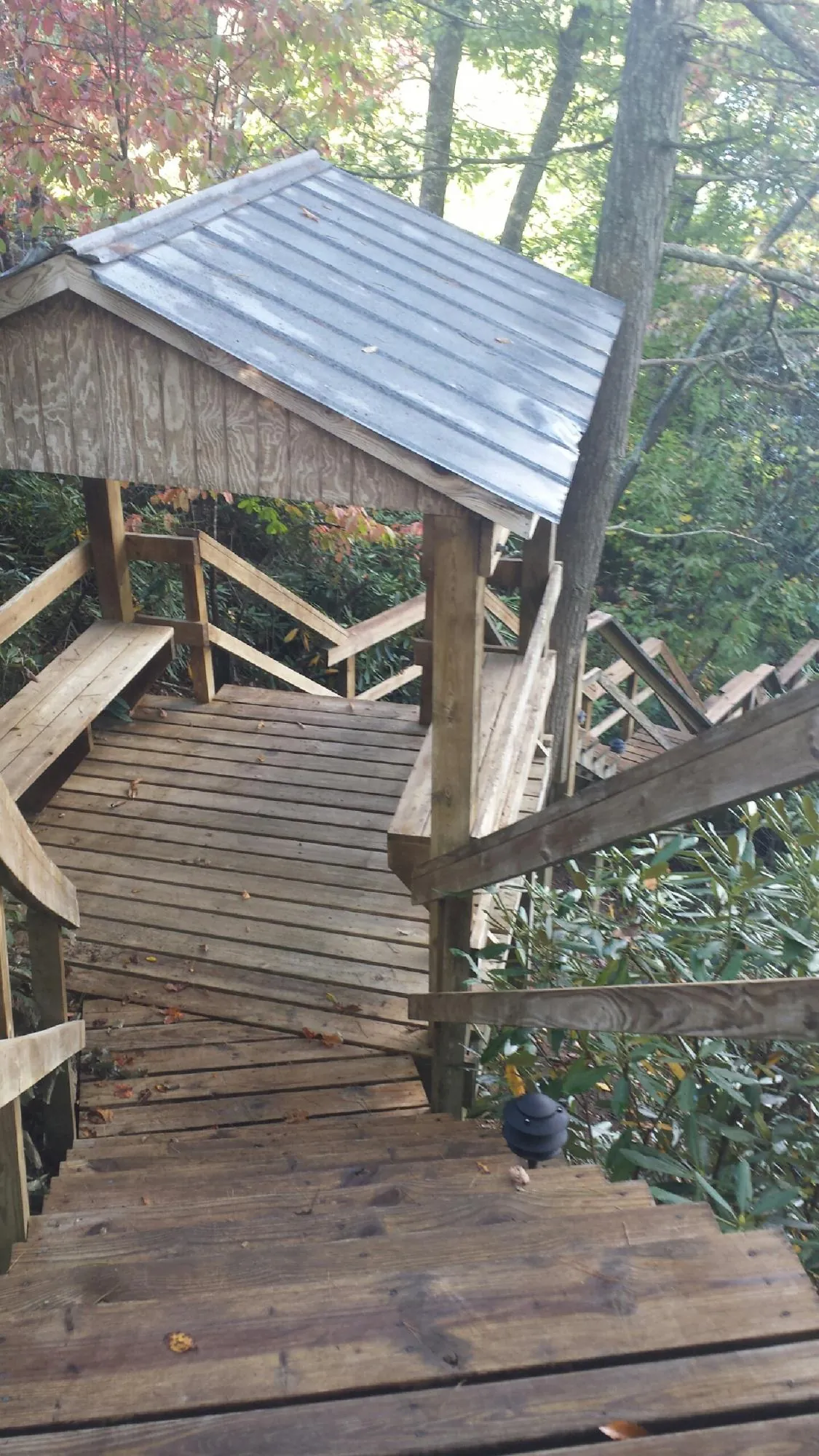 Metal roofed shelter over wooden steps on a wooded walkway — Skylight Repair & Installation work by our crew in Boxholm