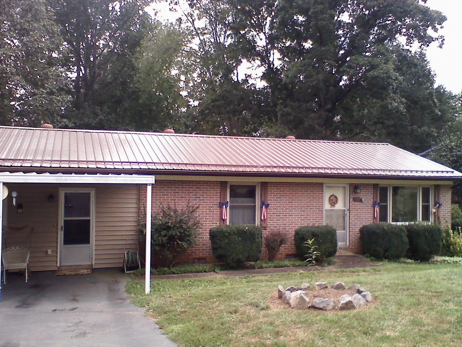 Bronze metal roof and carport on a brick ranch home — Roof Repair work by our crew in Boxholm