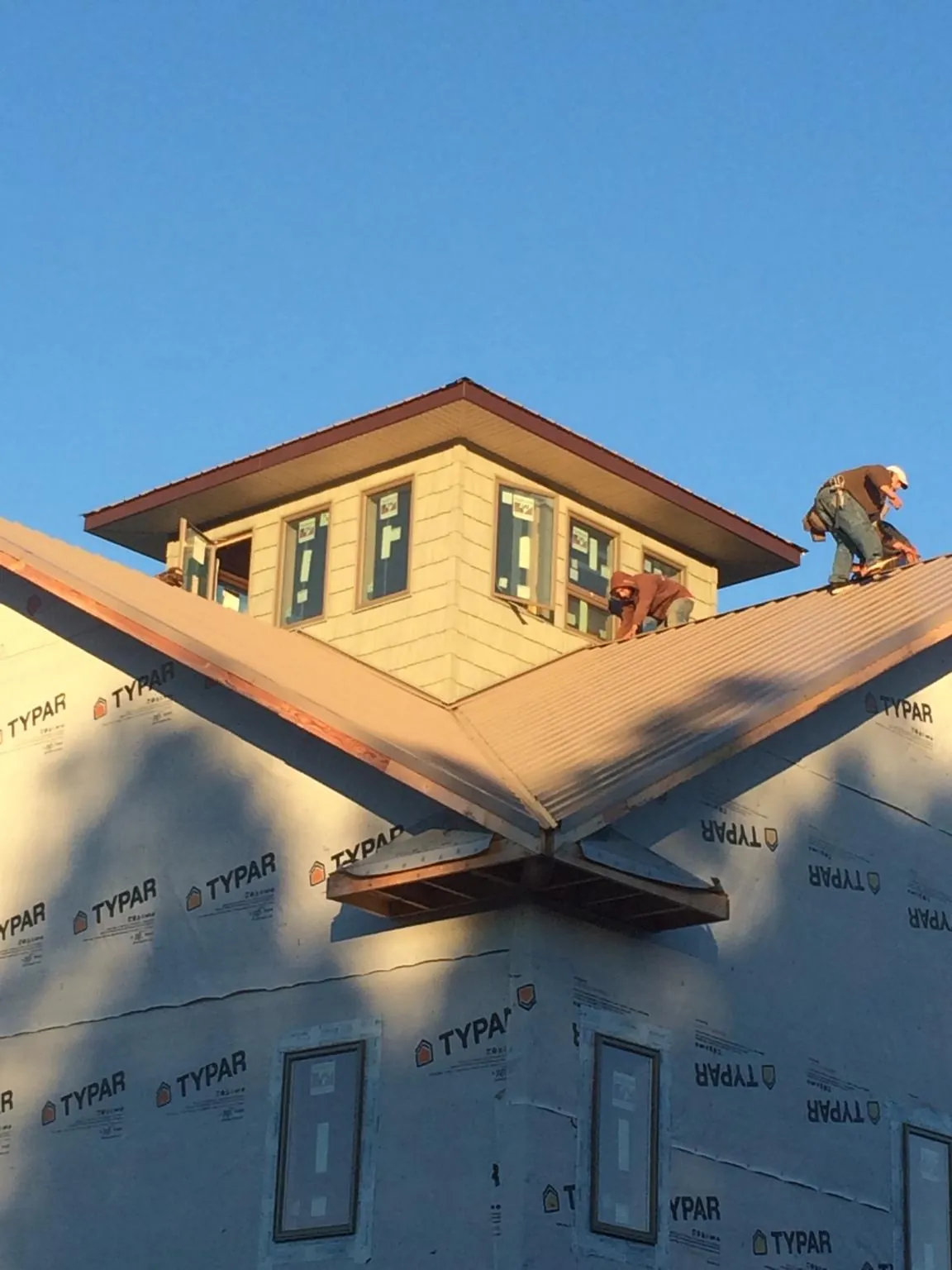 Roofers working around a rooftop cupola on a new metal roof at sunset — Roof Waterproofing in Boxholm by Roofing Brothers